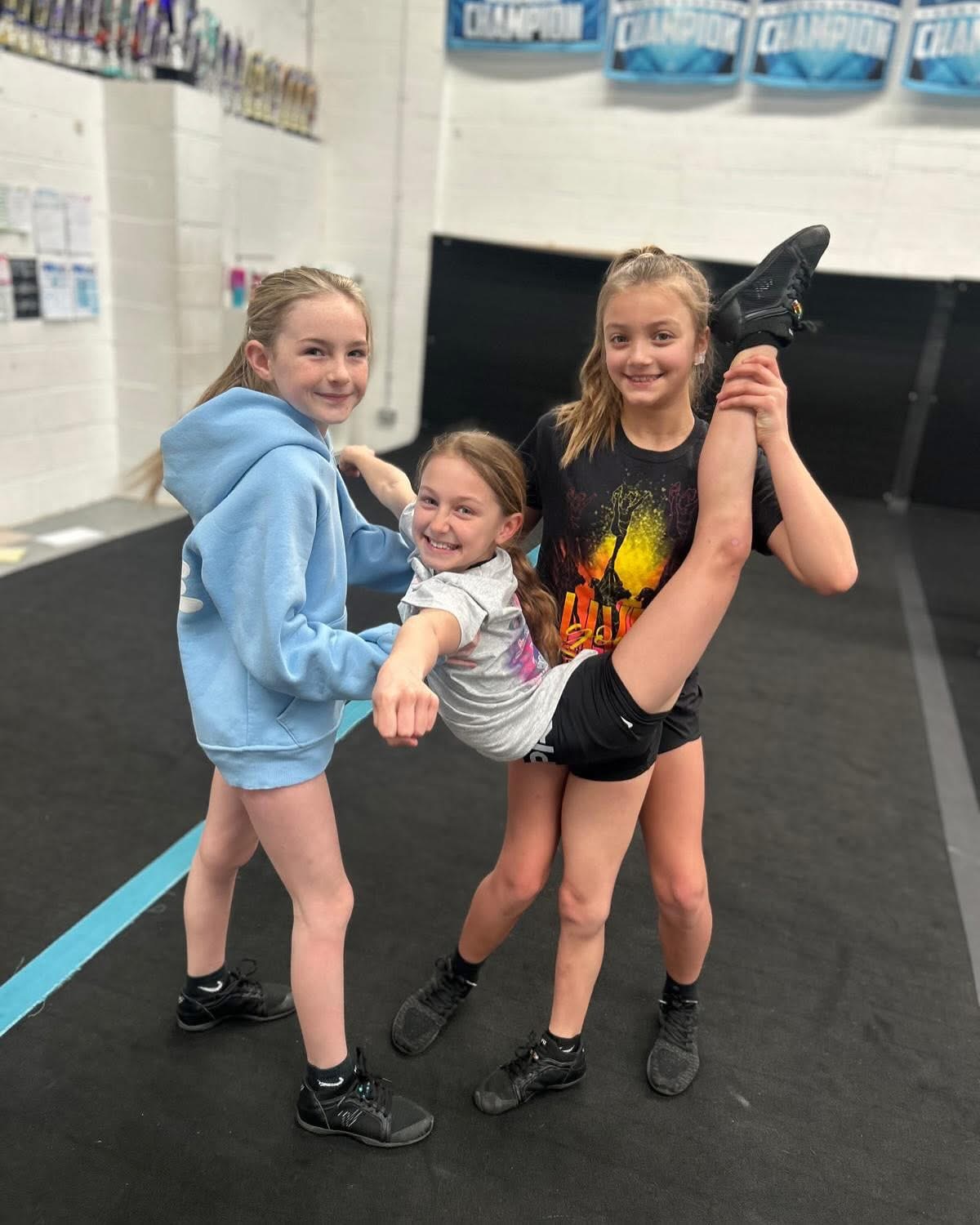 Three ACA cheerleaders holding a stretch pose together