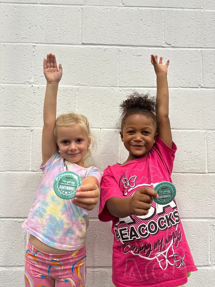 Two pre school ACA cheerleaders holding up their cartwheel badges