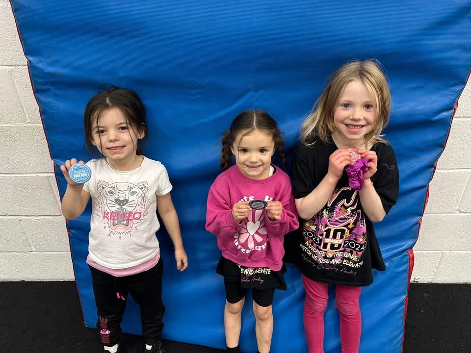 Three young ACA recreational cheerleaders showing their badges