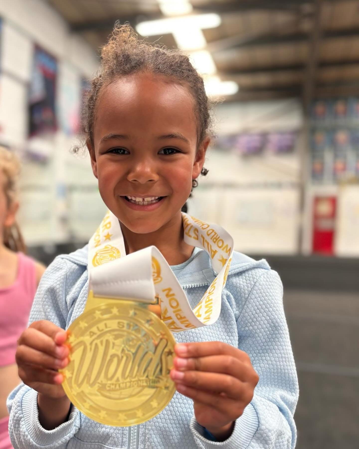 Young ACA cheerleader holding up a Worlds champion medal
