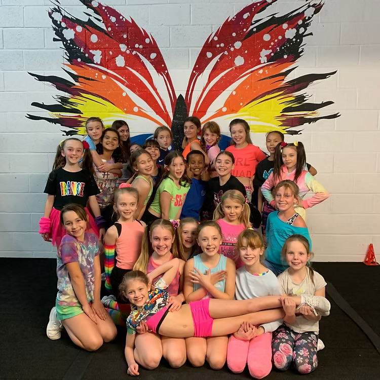 Large group of young ACA cheerleaders in front of the gym butterfly mural